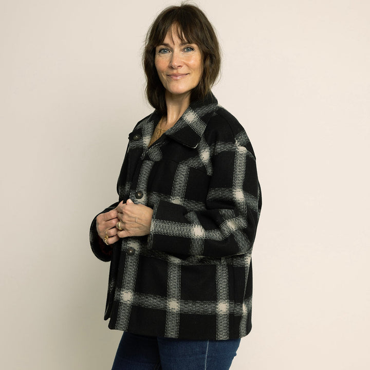 Woman wearing a stylish Car Coat Sewing Pattern in black and white plaid design, showcasing relaxed outerwear perfect for layering.