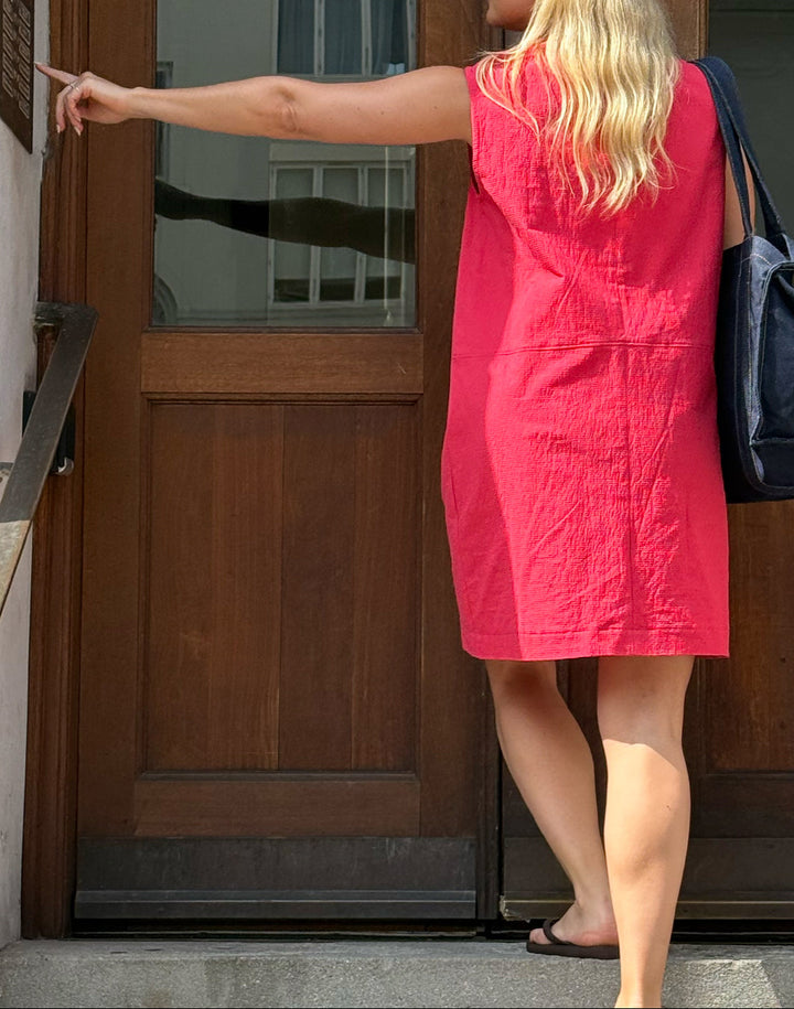 Woman in a red dress standing at a wooden door