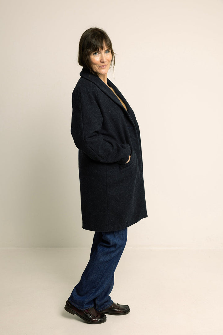 Person wearing a black coat and blue pants on a plain background
