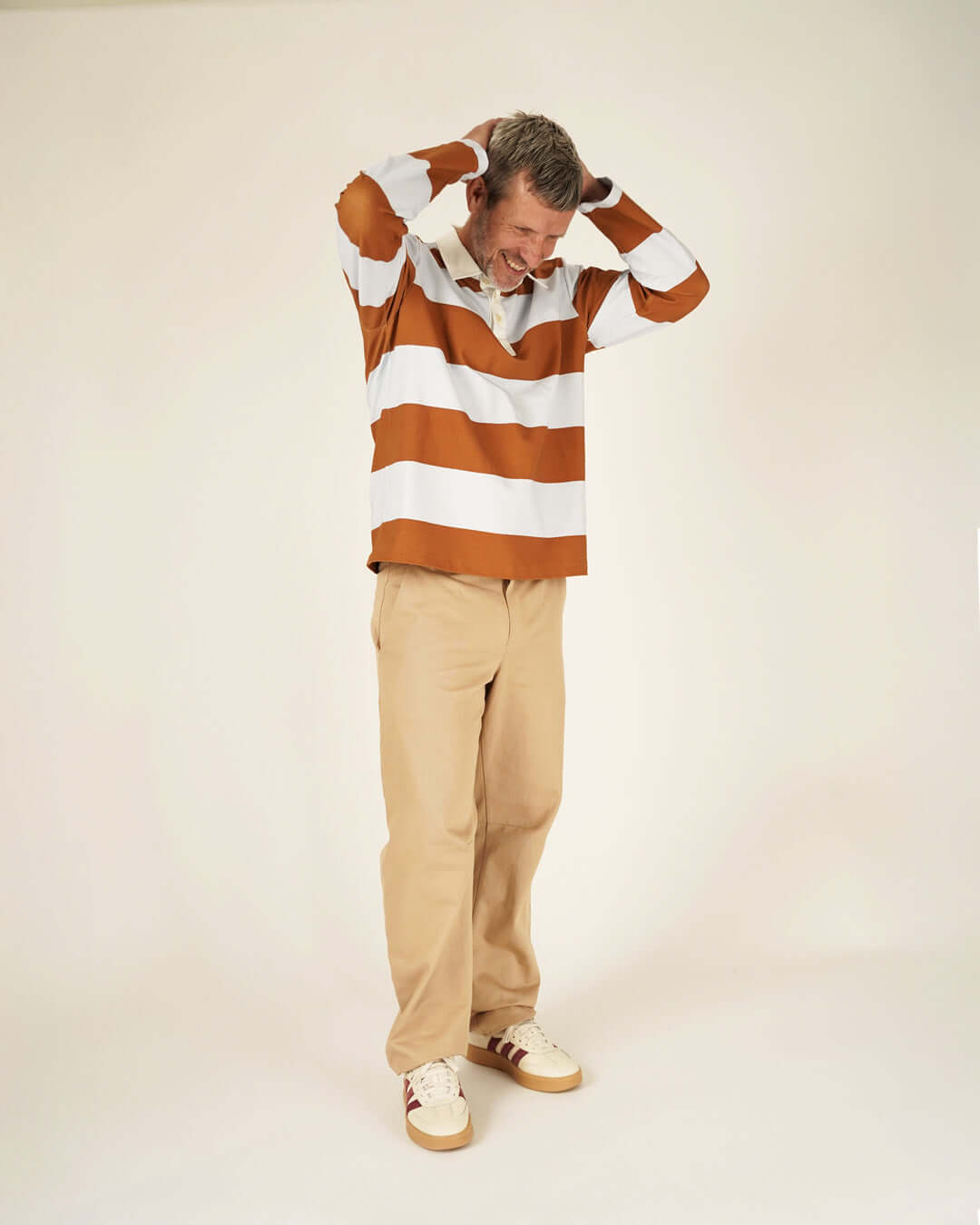Rugby Polo Shirt sewing pattern worn by a man, featuring brown and white stripes, paired with beige pants.