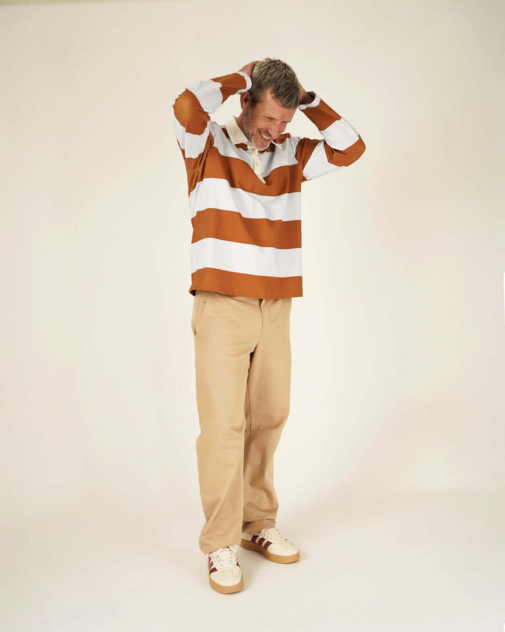 Rugby Polo Shirt sewing pattern worn by a man, featuring brown and white stripes, paired with beige pants.