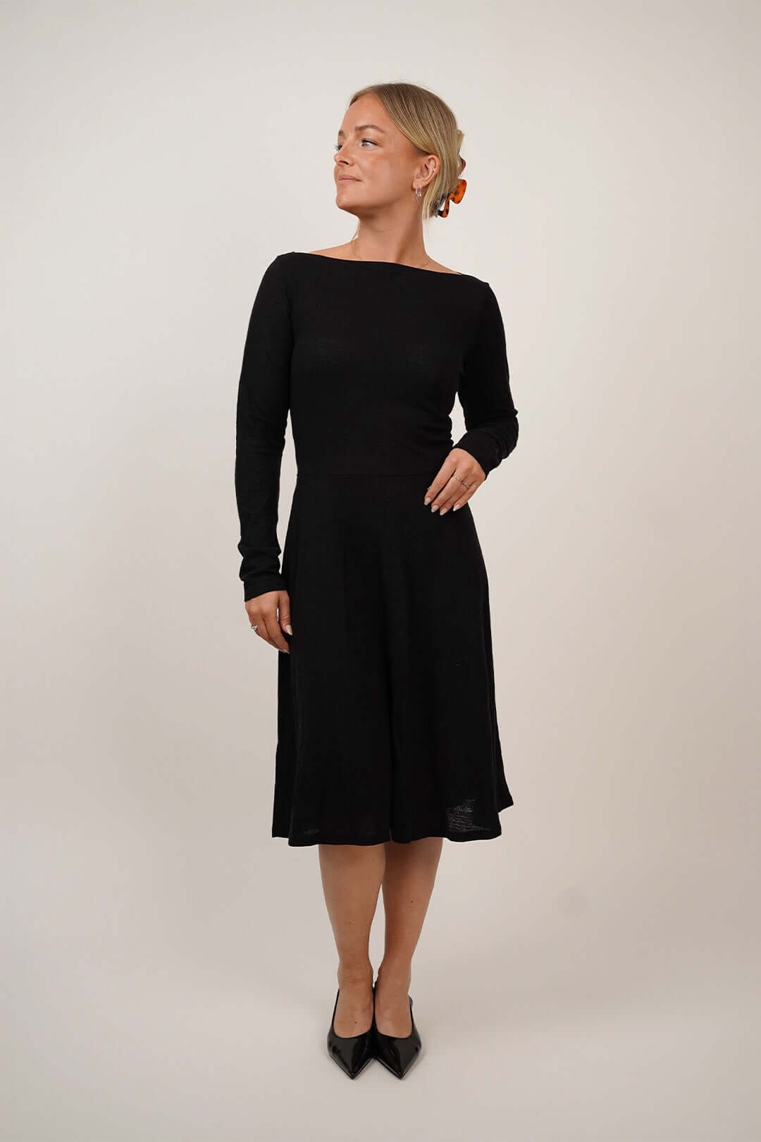 A model wearing a stylish long-sleeve The Little Black Dress, showcasing its elegant design and silhouette.