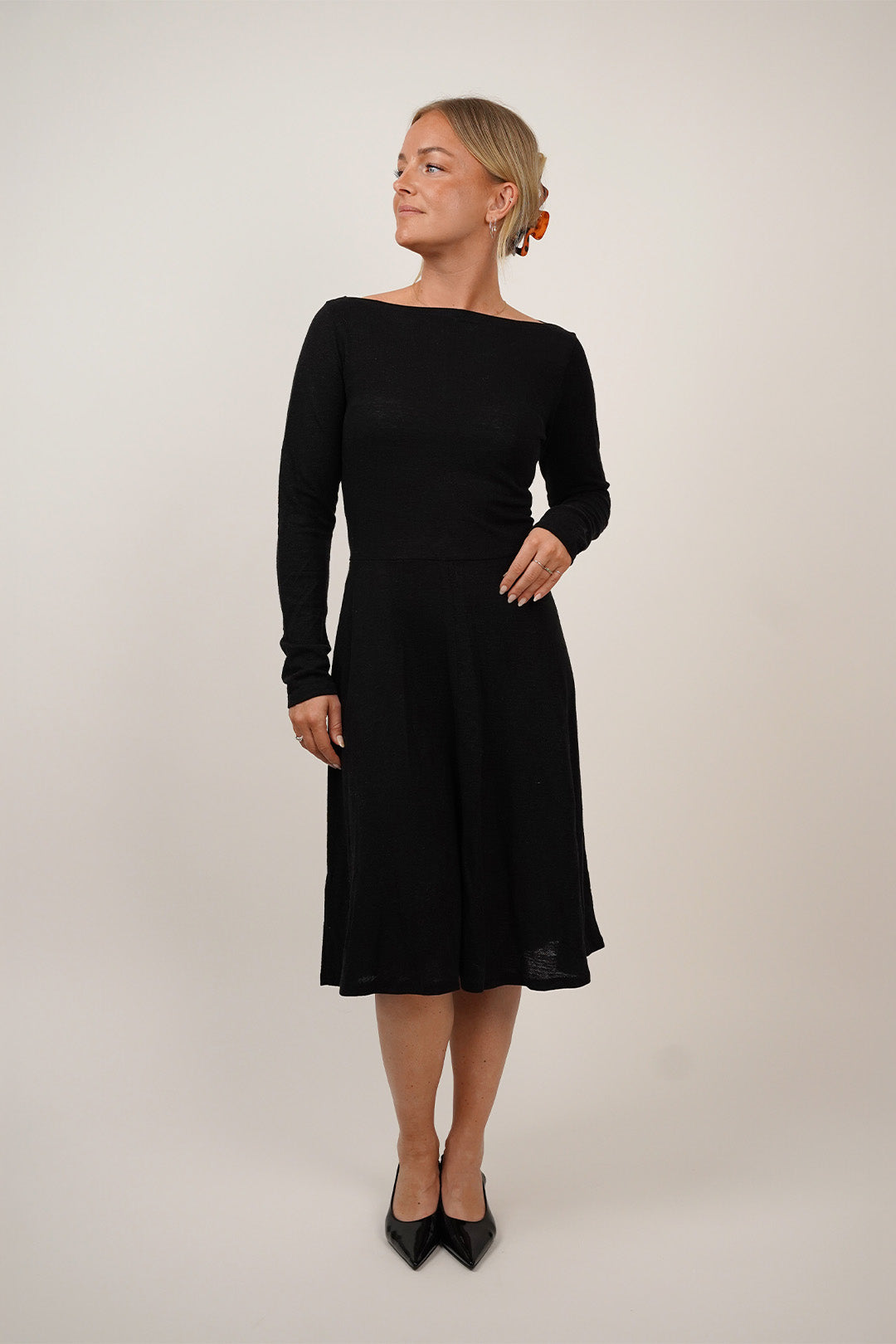 A model wearing a stylish long-sleeve The Little Black Dress, showcasing its elegant design and silhouette.
