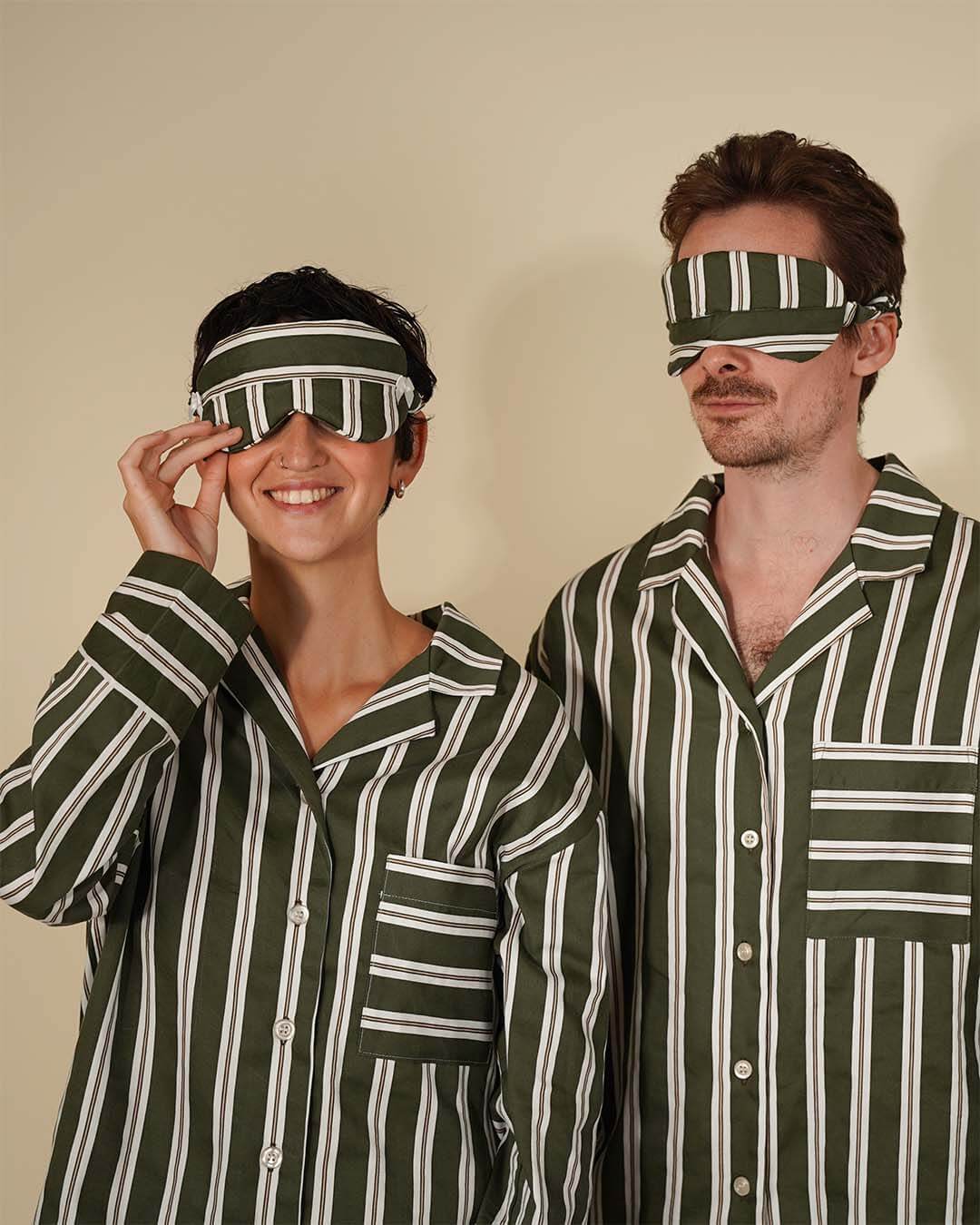 Couple wearing striped pajamas with free sleep mask PDF pattern on their eyes, smiling and posing.