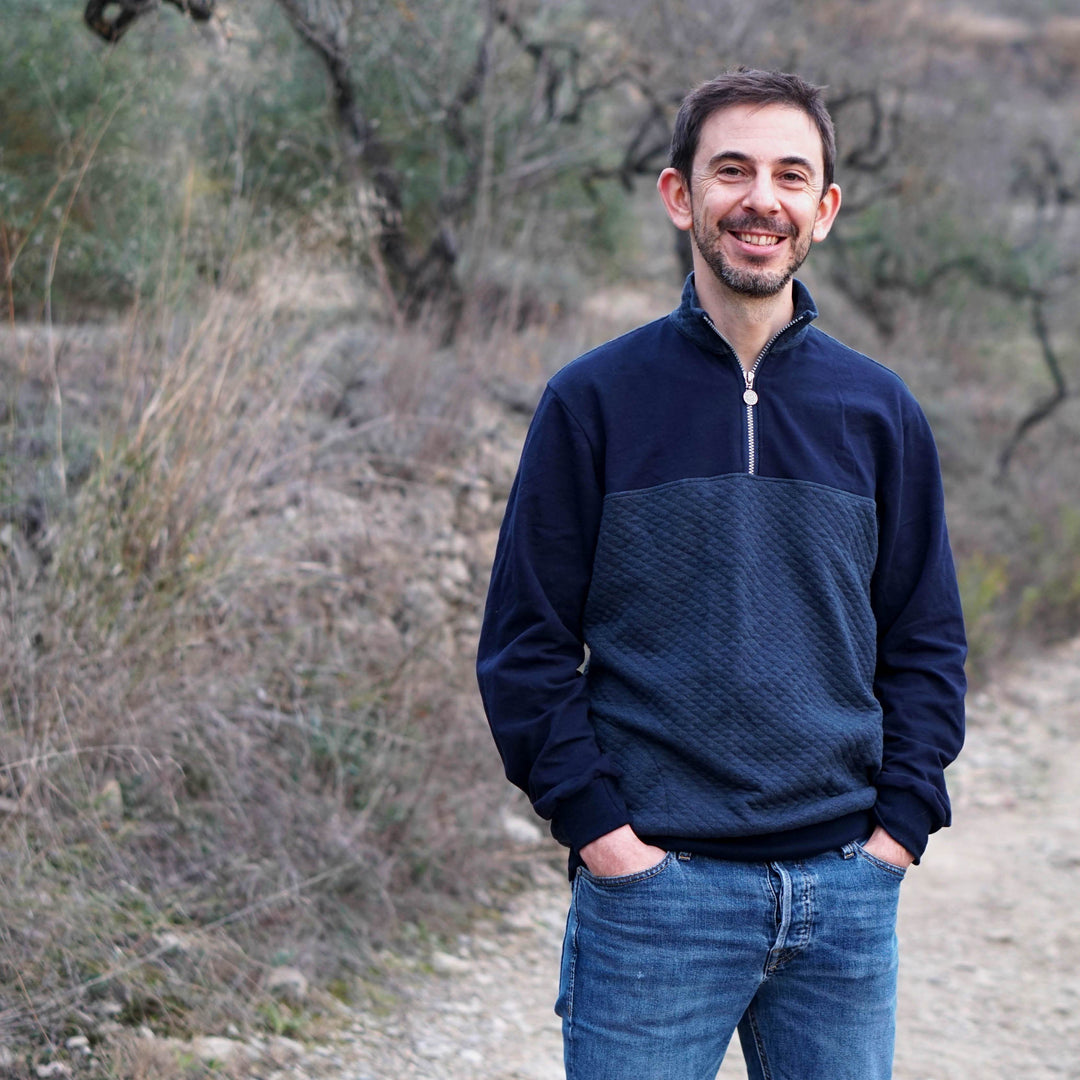 Man wearing a navy blue sweater in a natural setting, inspired by men's sweater sewing pattern.
