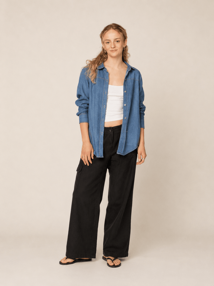 Model wearing a blue shirt styled with black pants, showcasing the Anna Shirt sewing pattern.