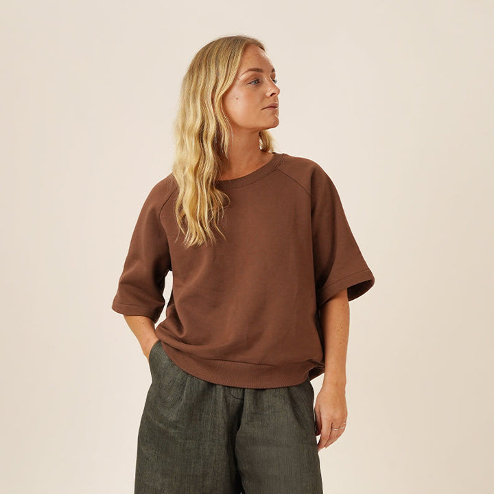Boxy Raglan Sewing Pattern model wearing a brown top and dark green shorts with knee-high boots