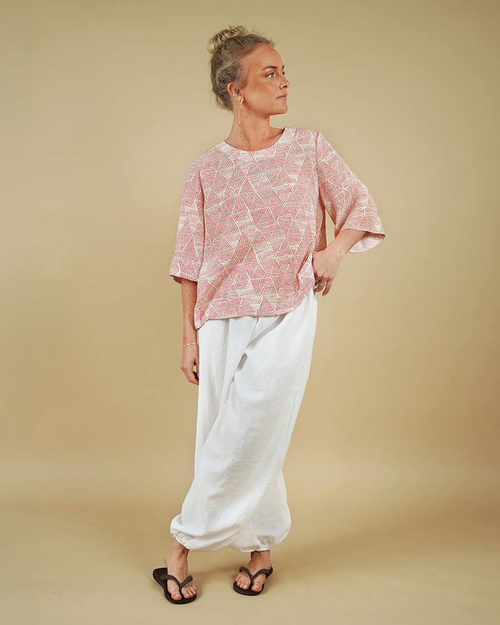 Woman modeling Bubble Pants sewing pattern with a geometric top against a plain background.