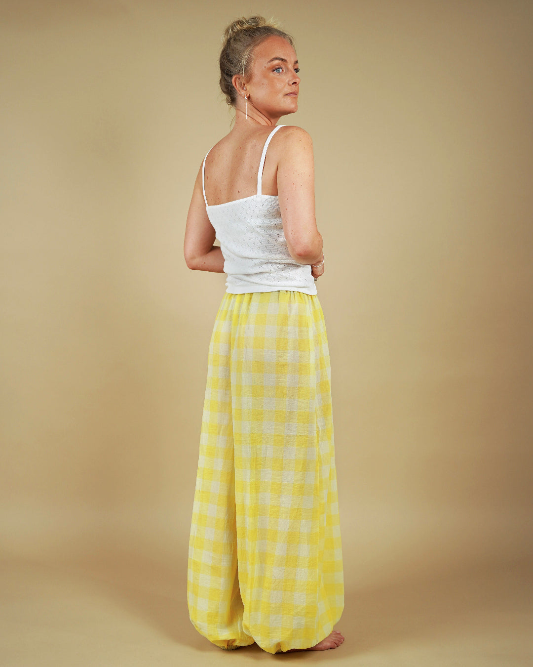 Back view of a model wearing yellow plaid Bubble Pants sewing pattern with a simple white top.
