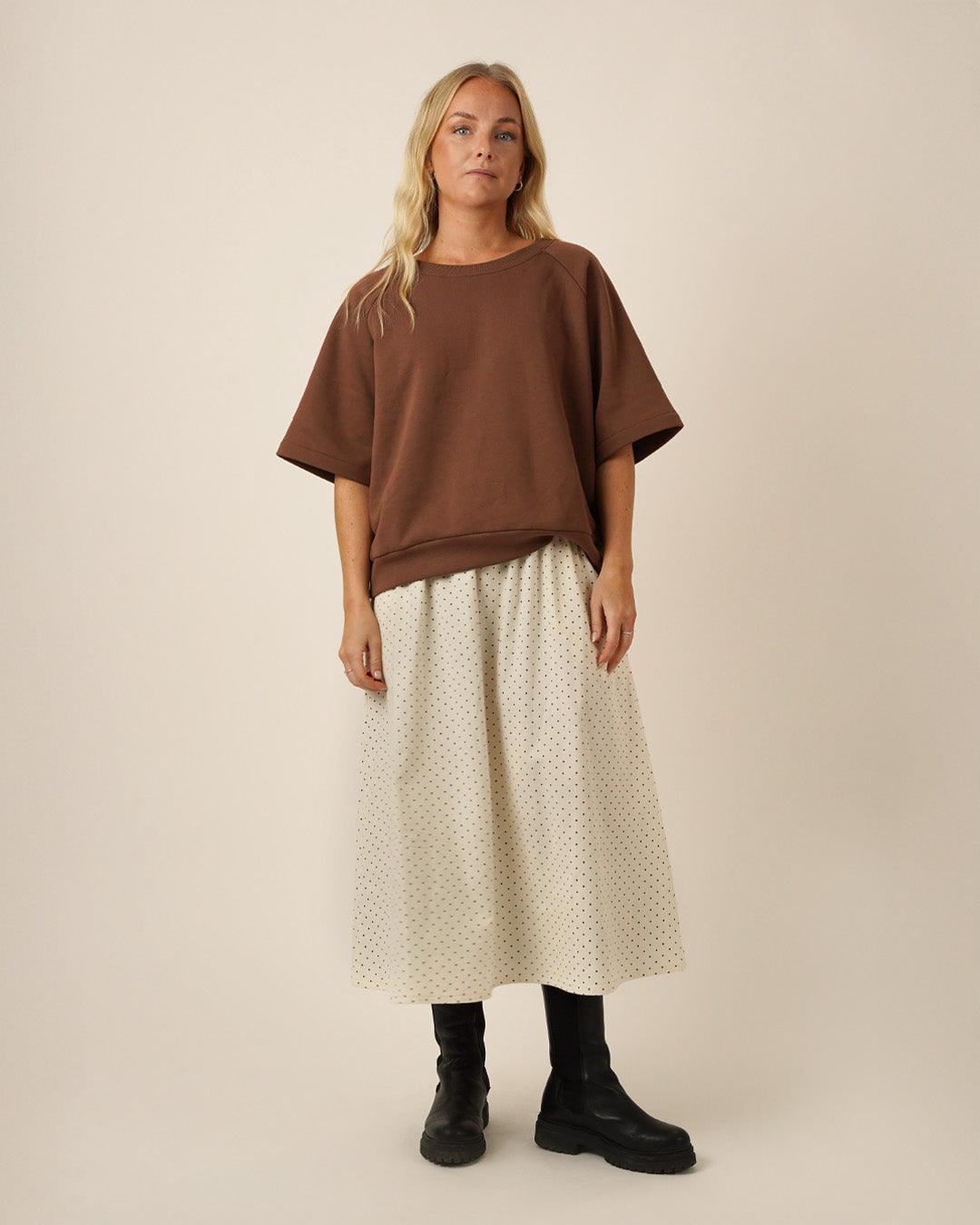 Woman wearing a brown Boxy Sweater sewing pattern, and a white Claude skirt sewing pattern