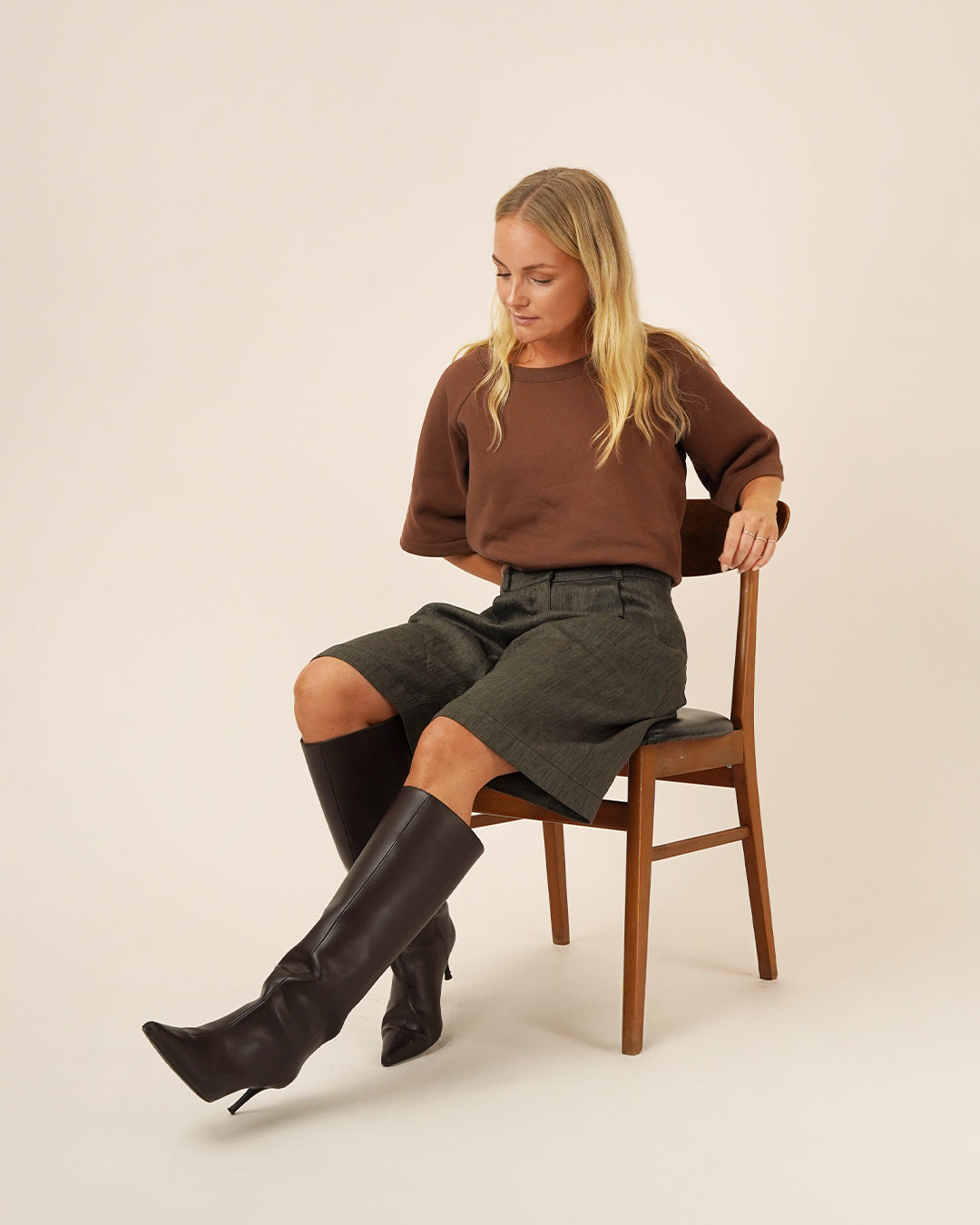 A model wearing Bermuda Pants and Shorts Sewing Pattern, styled with a brown top and knee-high boots.