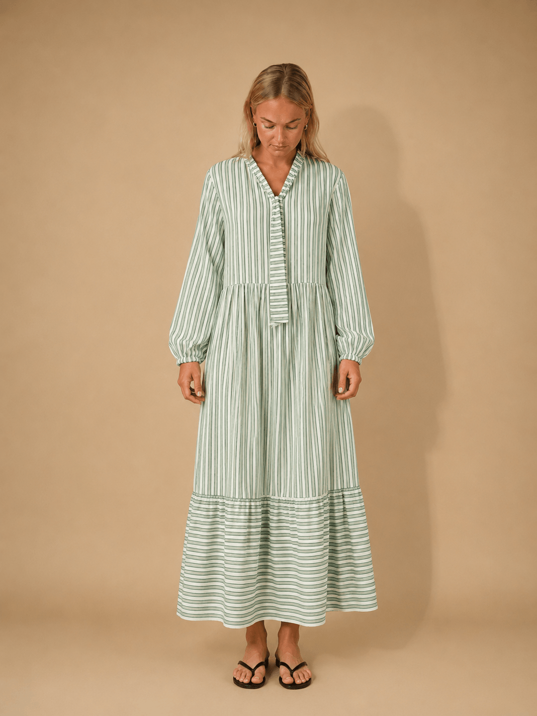 Woman wearing the Freedom dress sewing pattern, a relaxed striped dress with gathered skirt and button-down bodice.