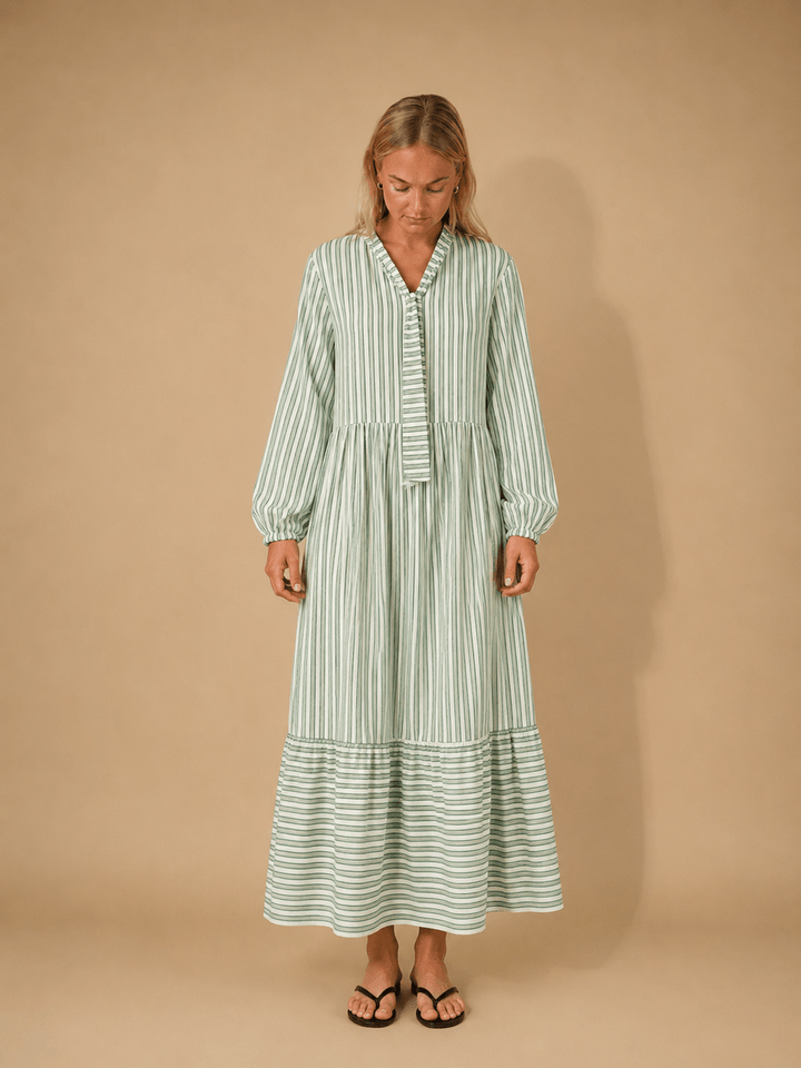 Woman wearing the Freedom dress sewing pattern, a relaxed striped dress with gathered skirt and button-down bodice.