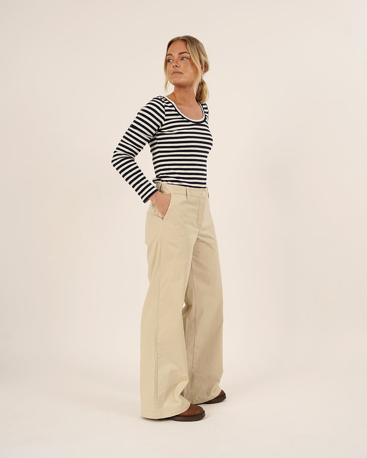 Woman wearing a striped shirt and beige pants on a white background