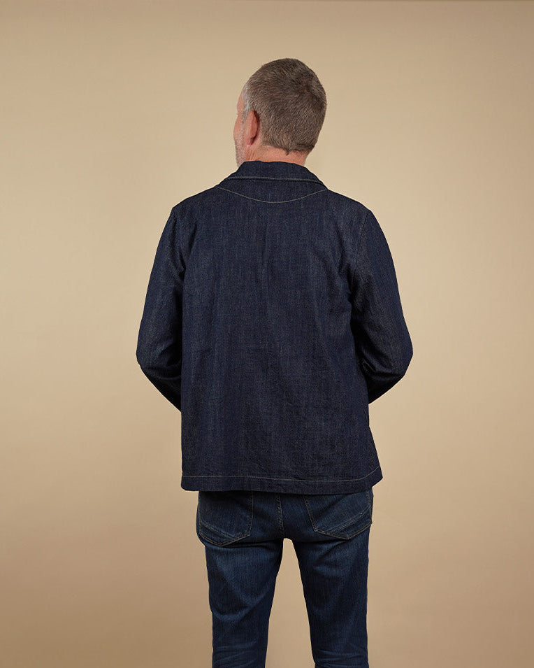 Man wearing a dark blue men's zip shirt sewing pattern and pants on a beige background