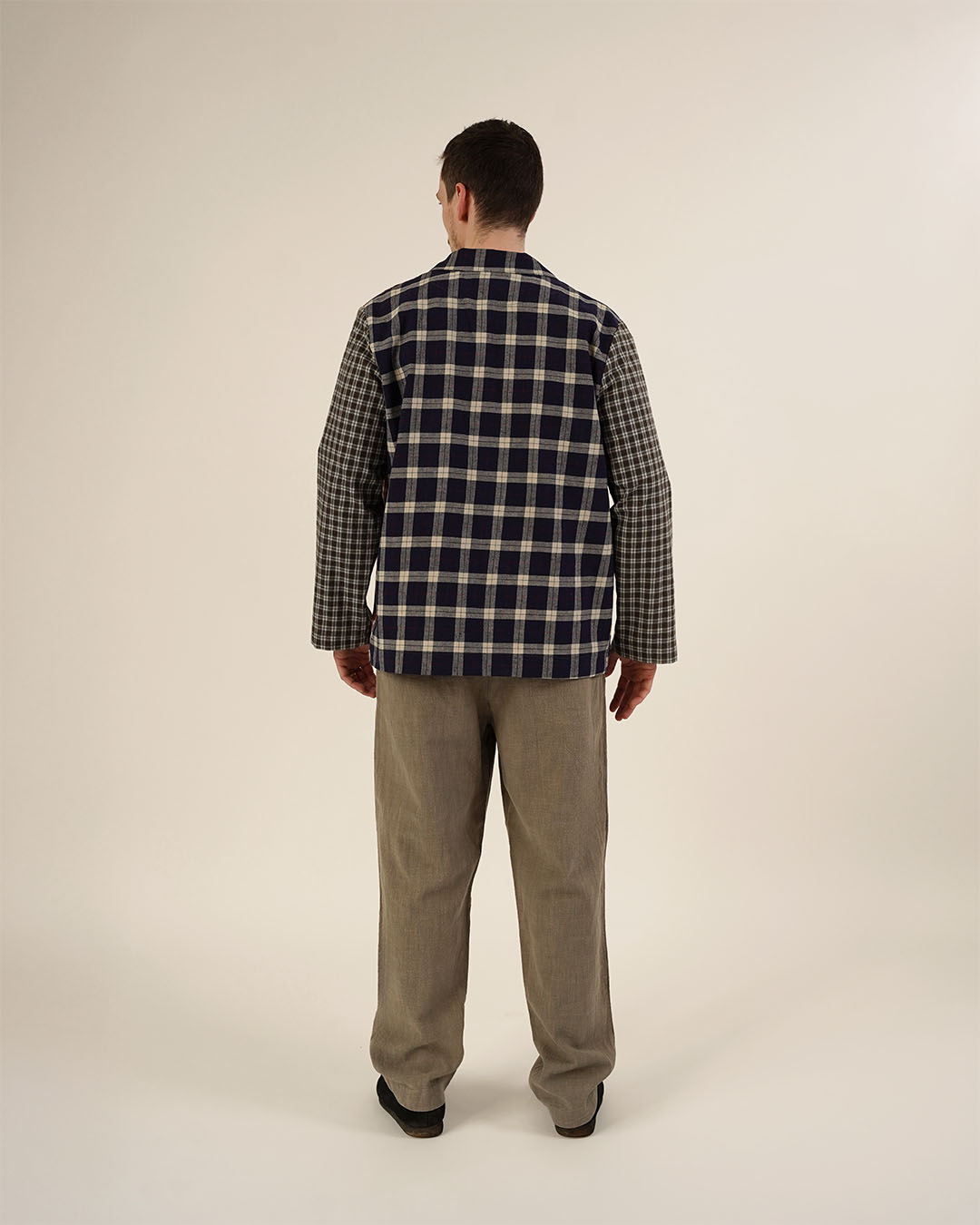Man wearing a checkered shirt and beige pants on a plain background