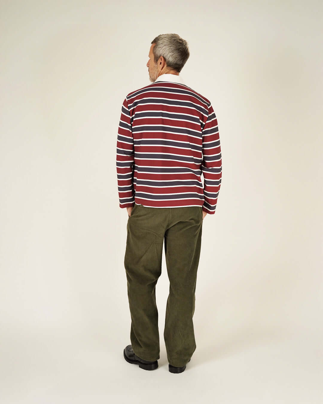 Man wearing a Rugby Polo Shirt sewing pattern in horizontal stripes, viewed from behind, paired with dark trousers.