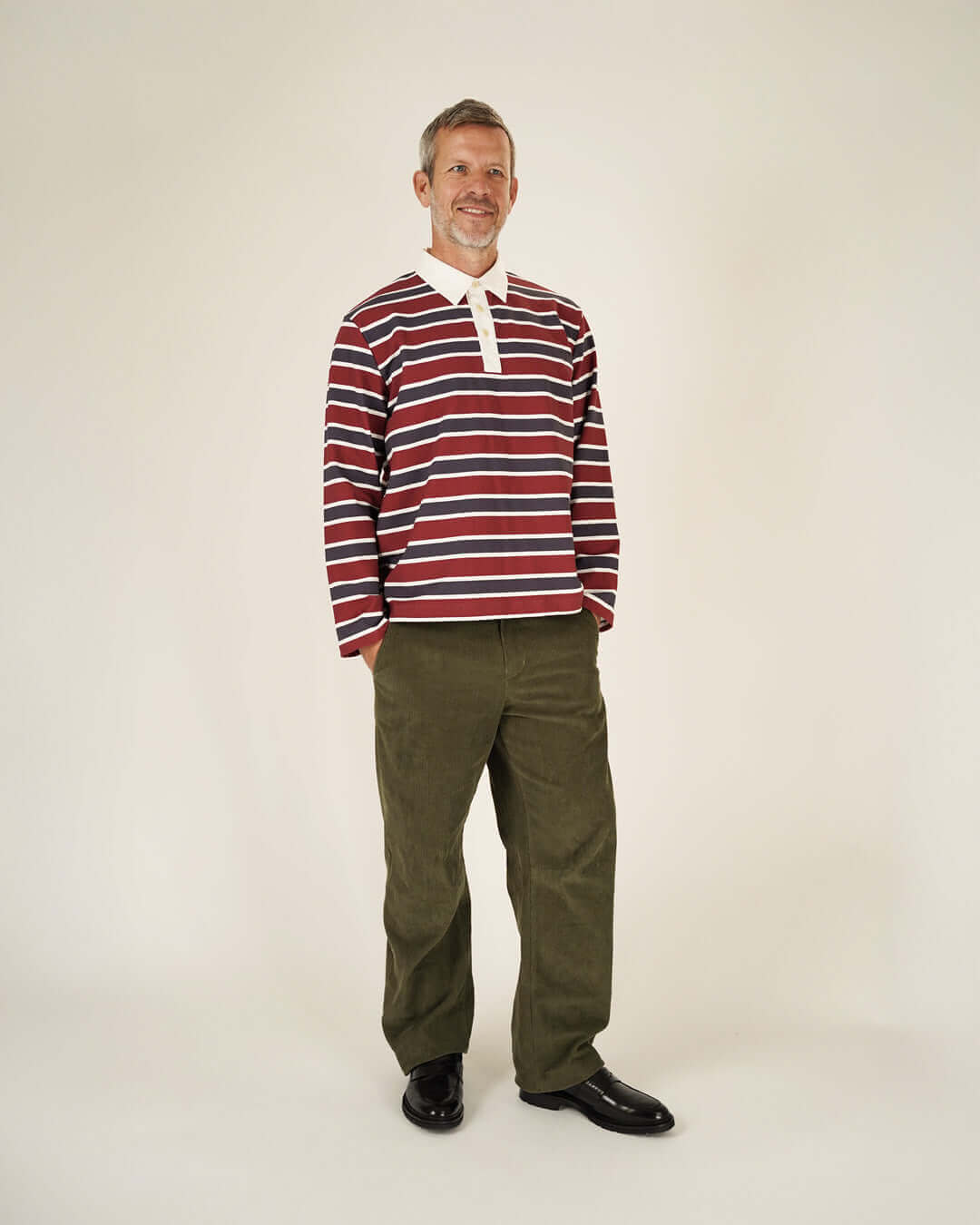 Rugby Polo Shirt sewing pattern worn by a man in a striped long-sleeve shirt and green pants.
