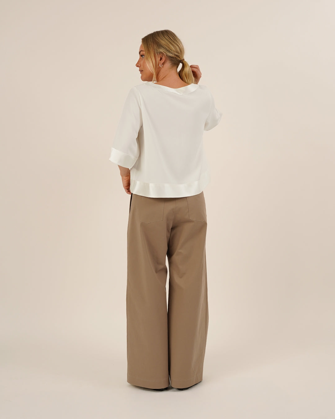 Woman wearing the Silke Blouse sewing pattern in white silk and a pair of Bermuda Pants