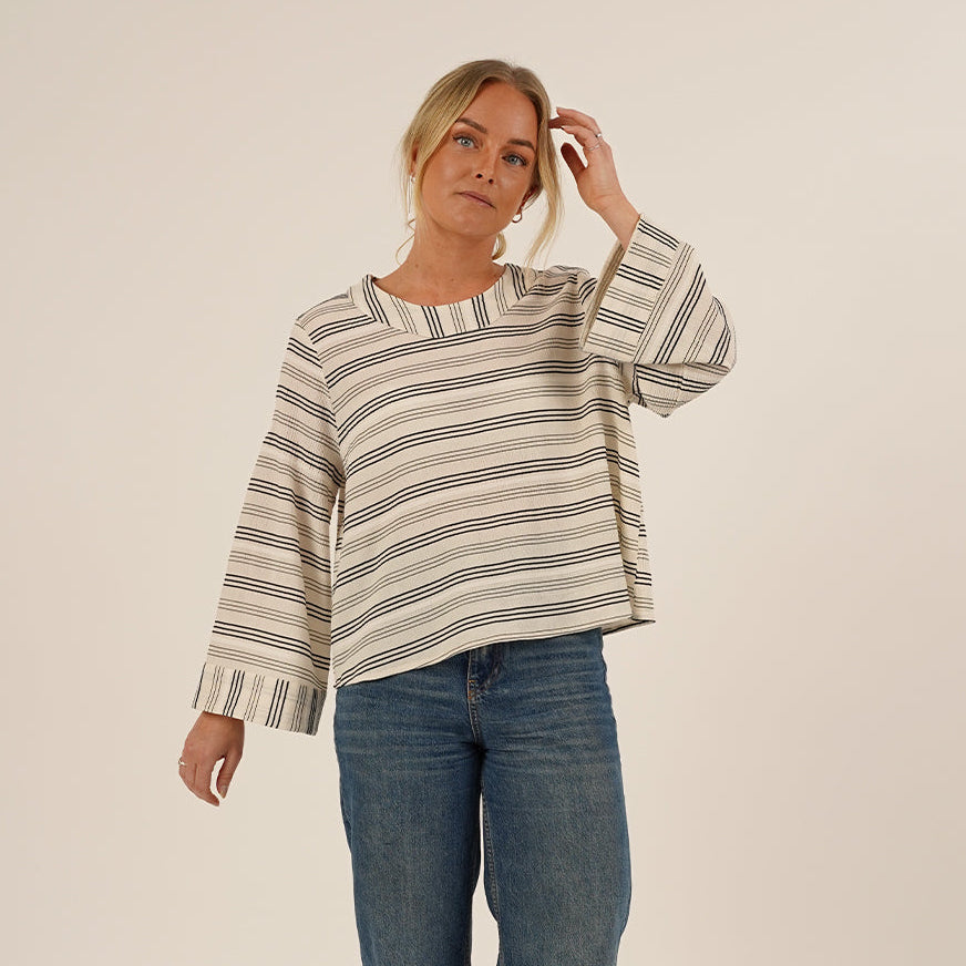 Woman wearing the Silke Blouse sewing pattern in Striped Viscose and a pair of Jeans