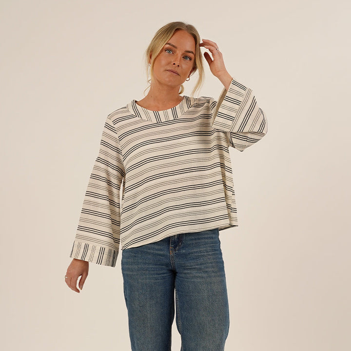 Woman wearing the Silke Blouse sewing pattern in Striped Viscose and a pair of Jeans