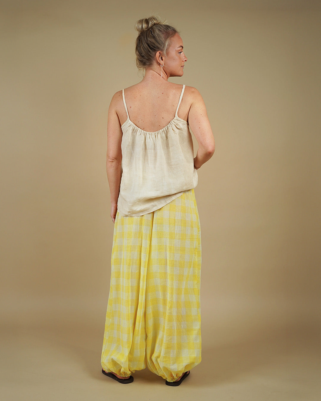 Woman wearing Bubble Pants sewing pattern in yellow checkered fabric, showing the floaty silhouette from the back.