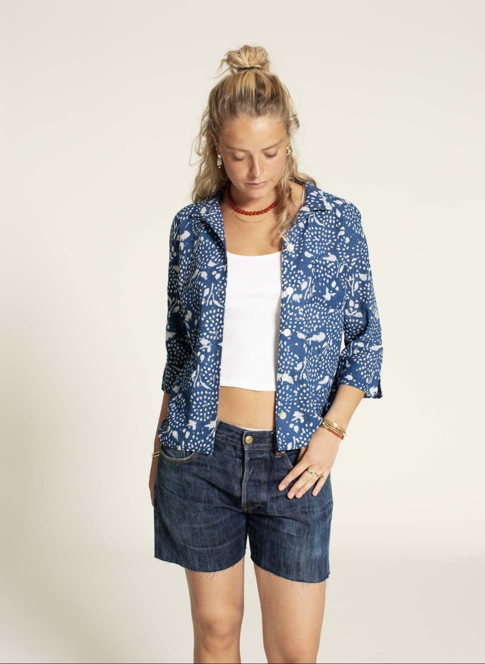 Woman wearinga blue shirt with denim shorts 
