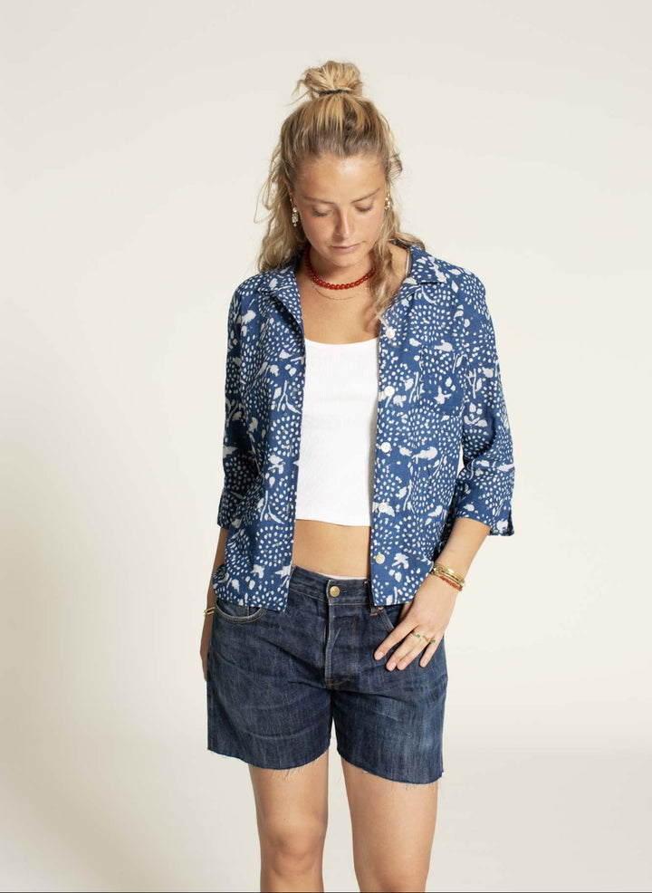 Woman wearinga blue shirt with denim shorts 
