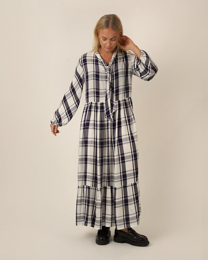 Woman wearing a black and white checkered freedom dress sewing pattern on a beige background