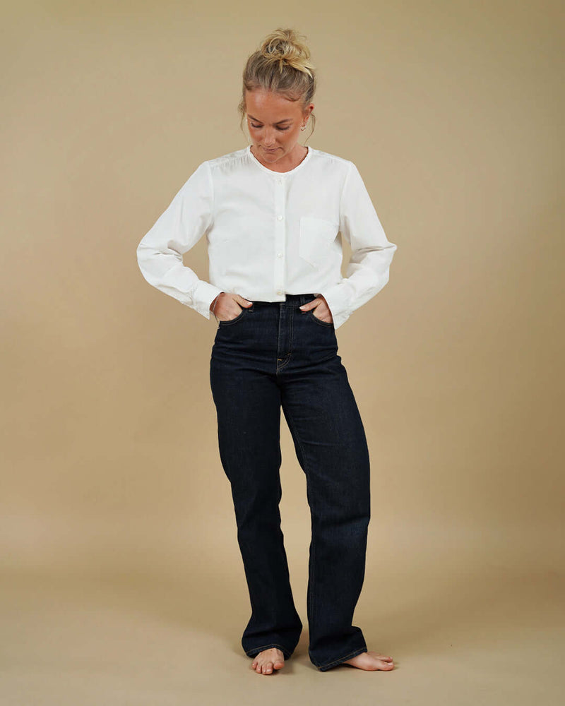 Person wearing a white blouse and black pants on a beige background