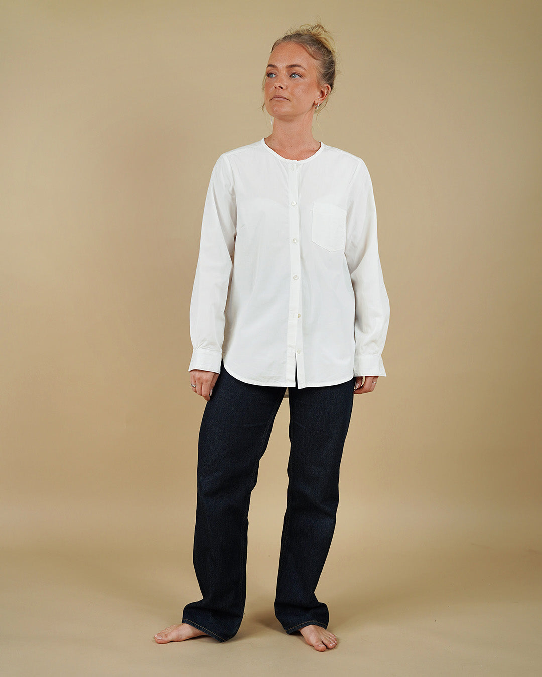 Person wearing a white cardigan and black pants on a beige background