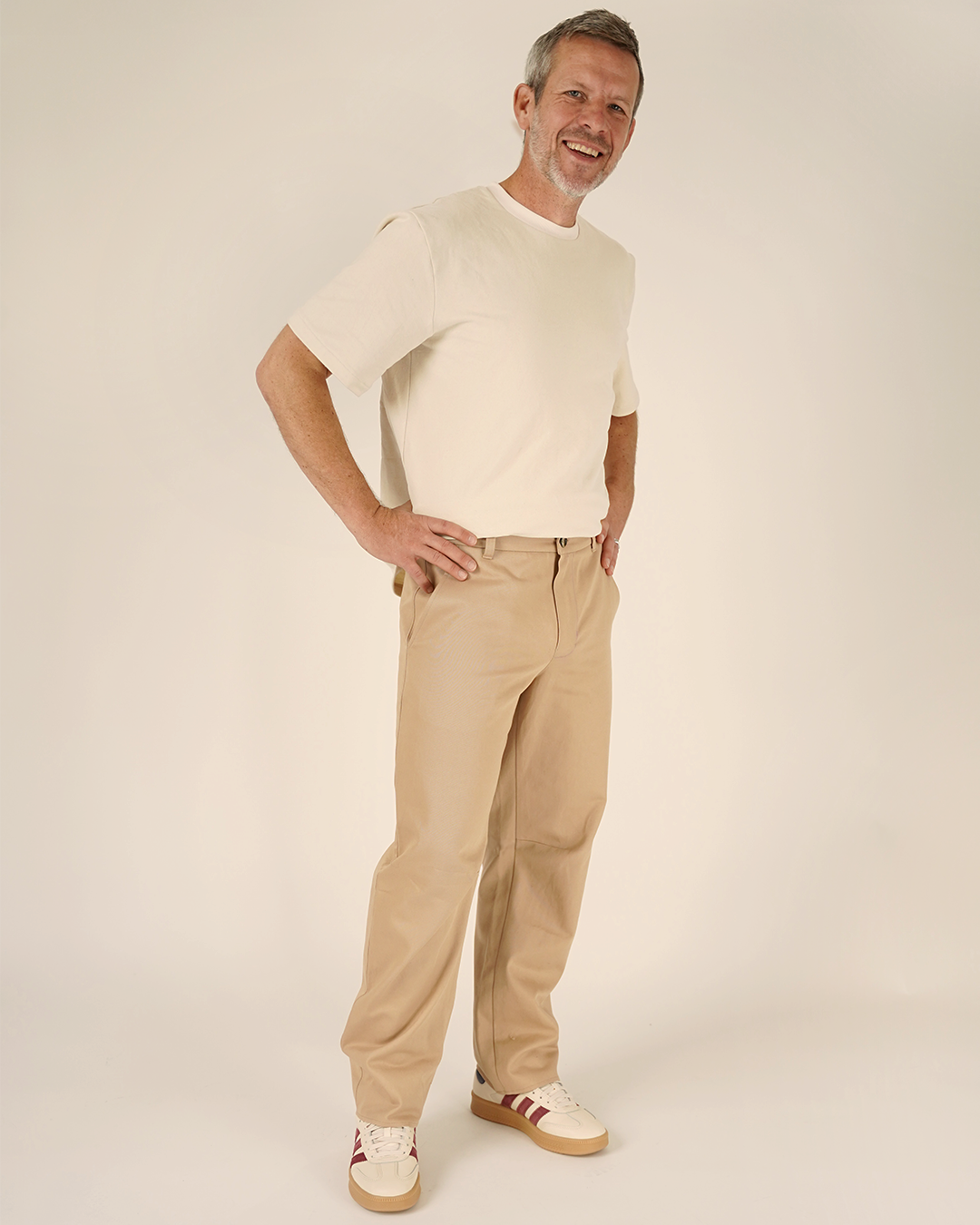 Man wearing a cream sweater and beige pants on a plain background