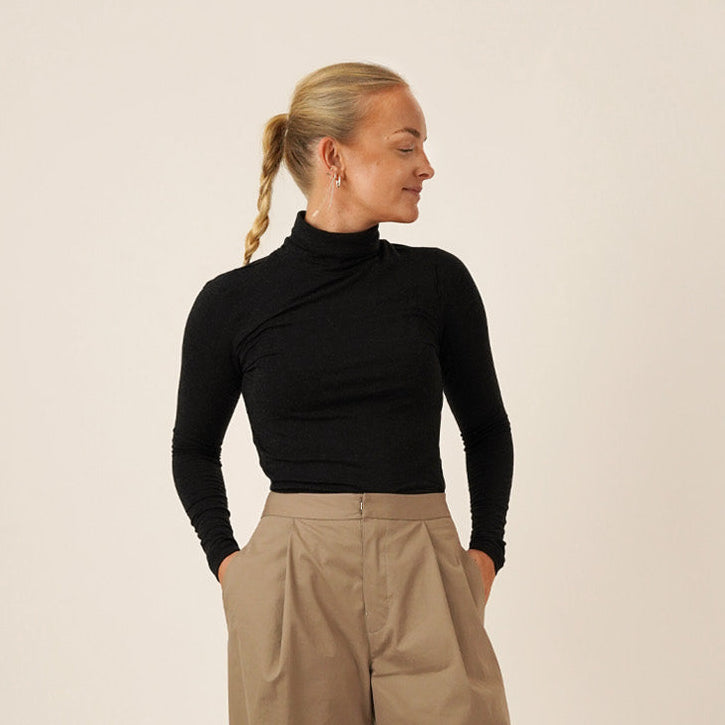 Woman wearing Bermuda pants and a black trudy turtleneck T-shirt, showcasing the Bermuda Pants and Shorts Sewing Pattern.
