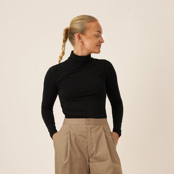 Woman wearing Bermuda pants and a black trudy turtleneck T-shirt, showcasing the Bermuda Pants and Shorts Sewing Pattern.