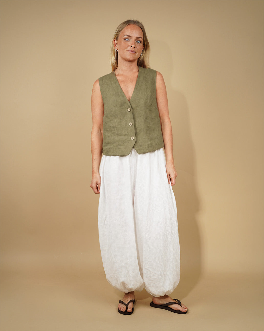 Model wearing a relaxed Waistcoat top sewing pattern with deep V-neckline and button closure, paired with white flowy pants.