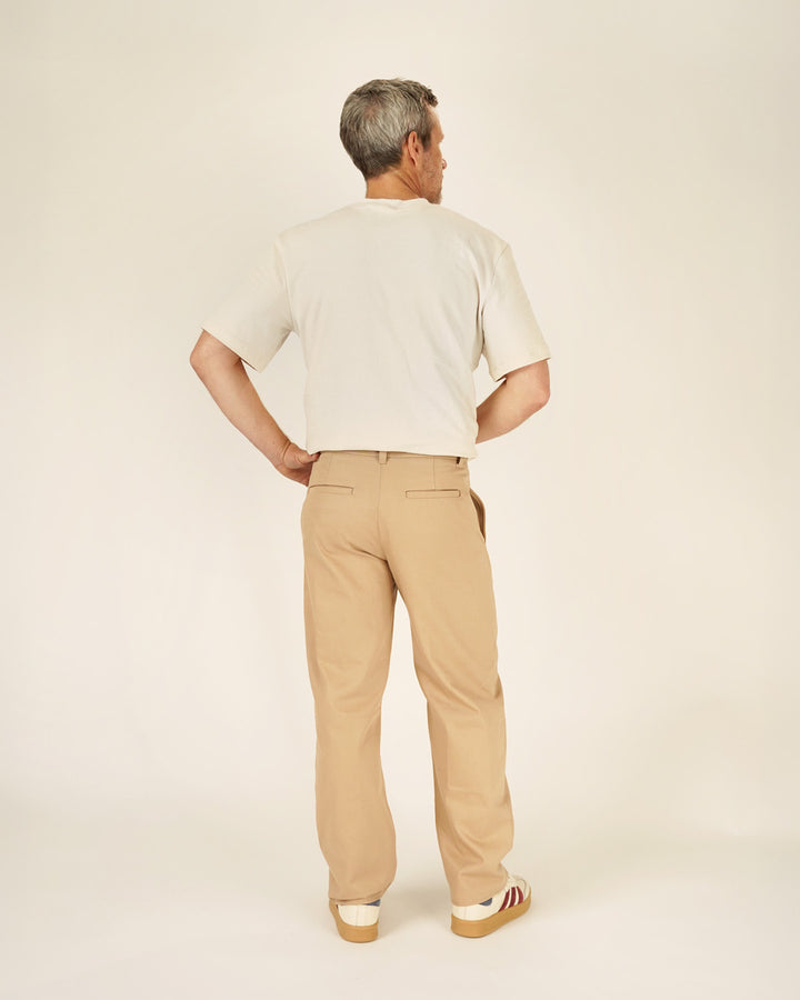 Person wearing a beige shirt and tan pants on a plain background
