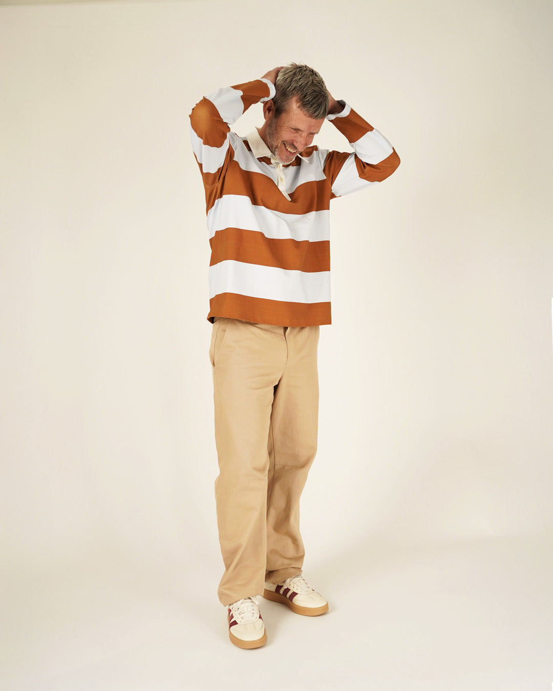Man wearing a striped sweater and beige pants on a white background