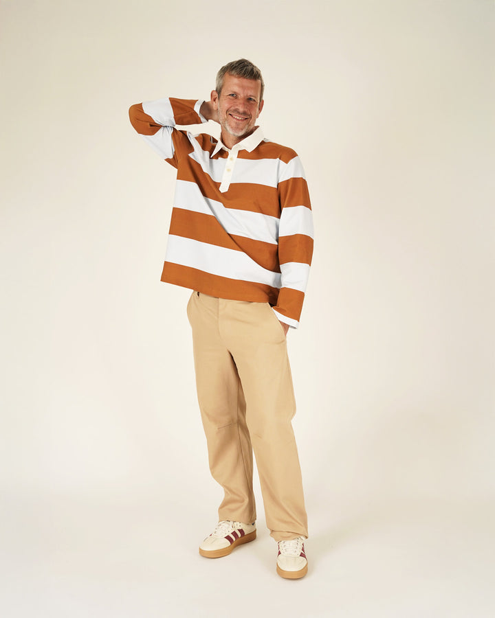 Man wearing a striped sweater and beige pants on a white background