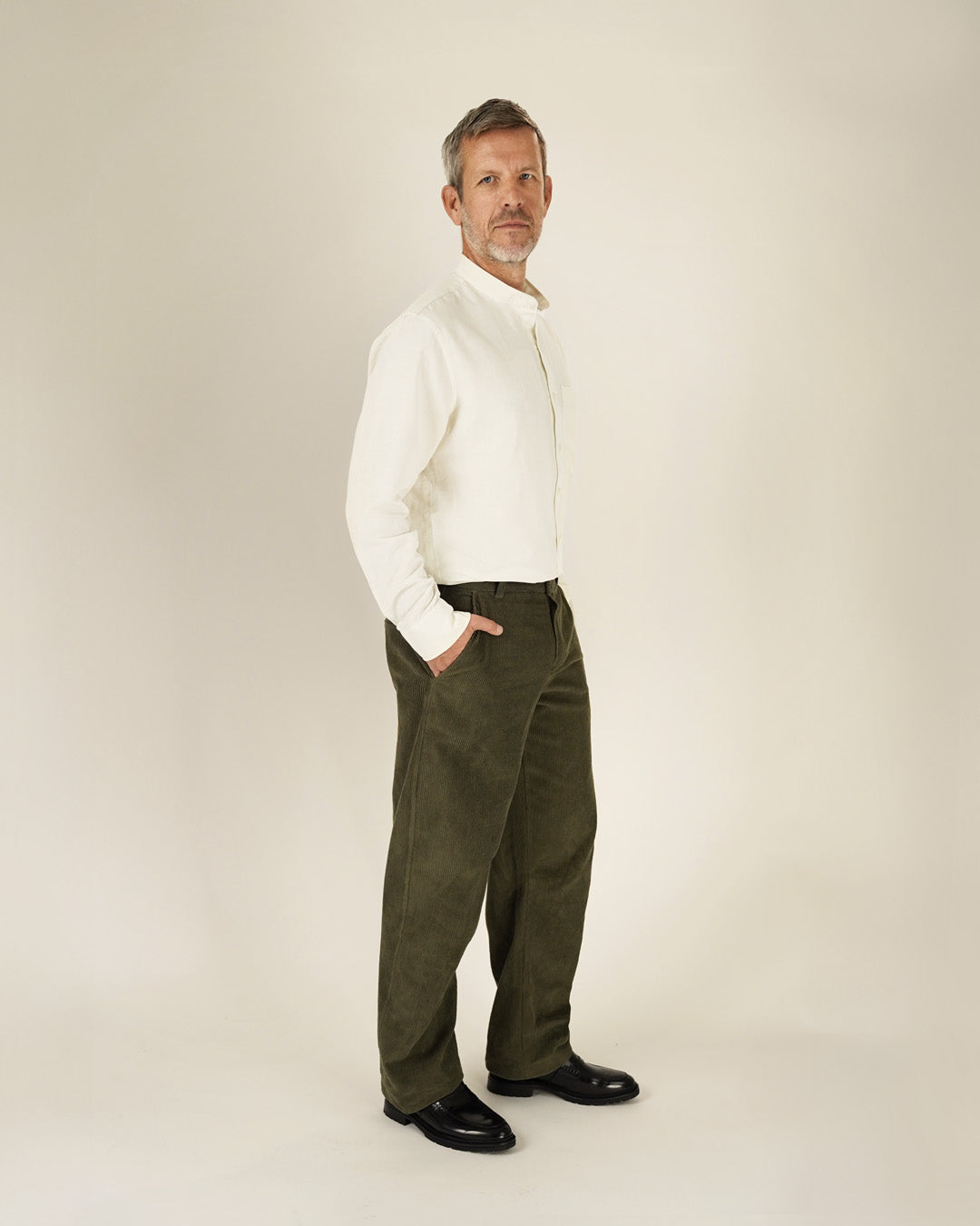 Man wearing a white turtleneck sweater and green pants on a beige background