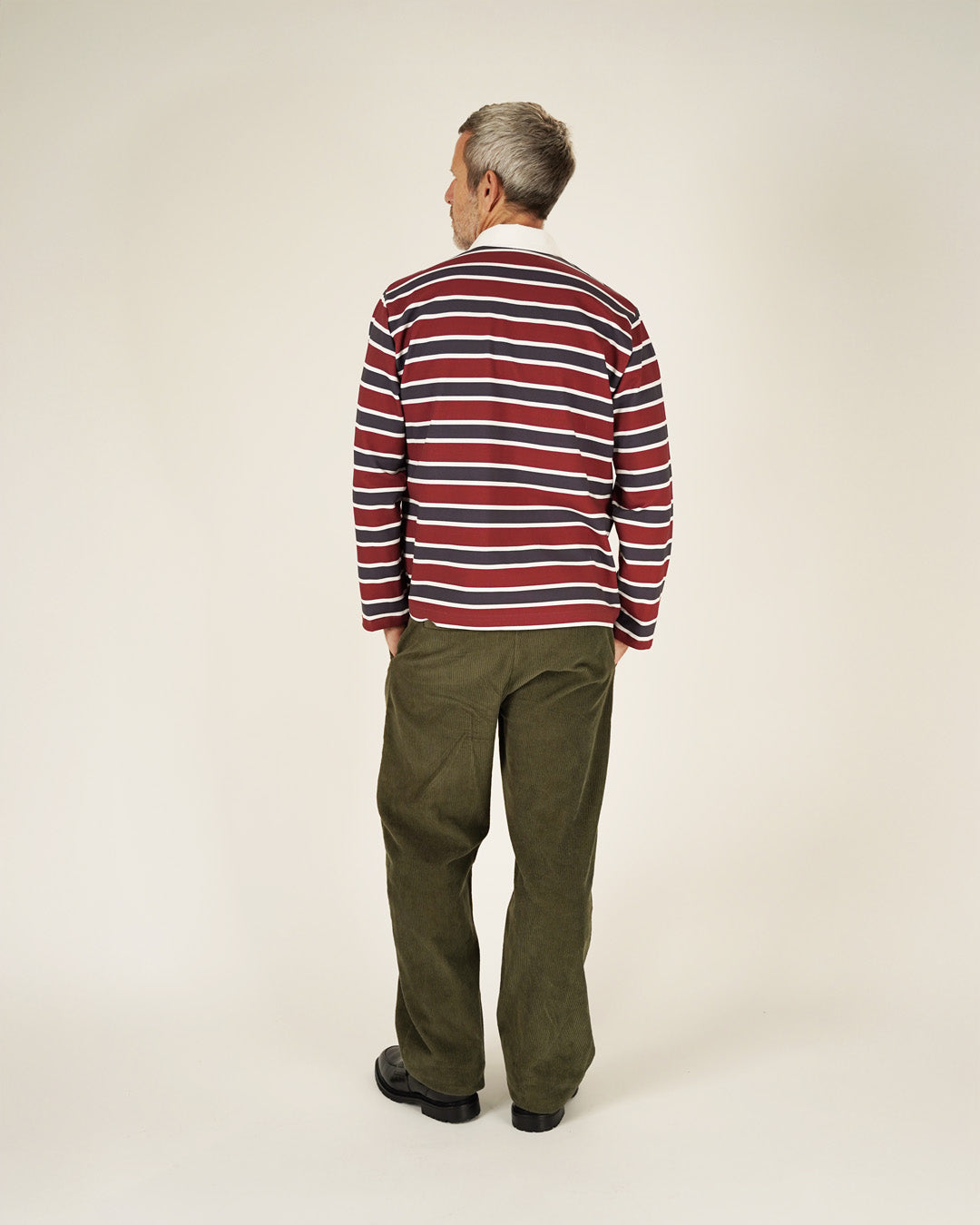 Man wearing a red and blue striped sweater and green pants on a white background