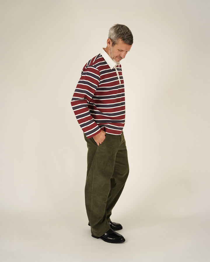 Man wearing a striped sweater and green pants on a white background