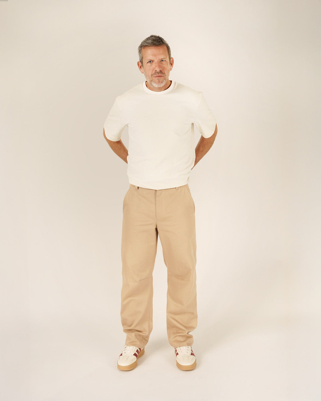 Man wearing a relaxed Big T-shirt sewing pattern in white with beige trousers, showcasing modern style and comfort.