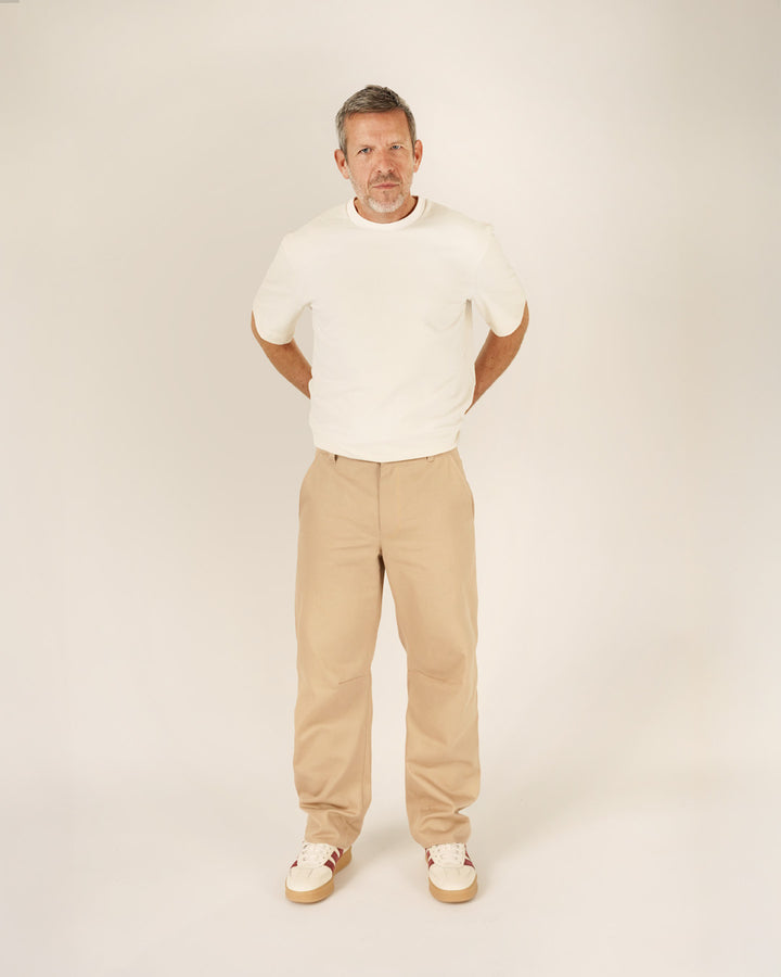 Man wearing a relaxed Big T-shirt sewing pattern in white with beige trousers, showcasing modern style and comfort.