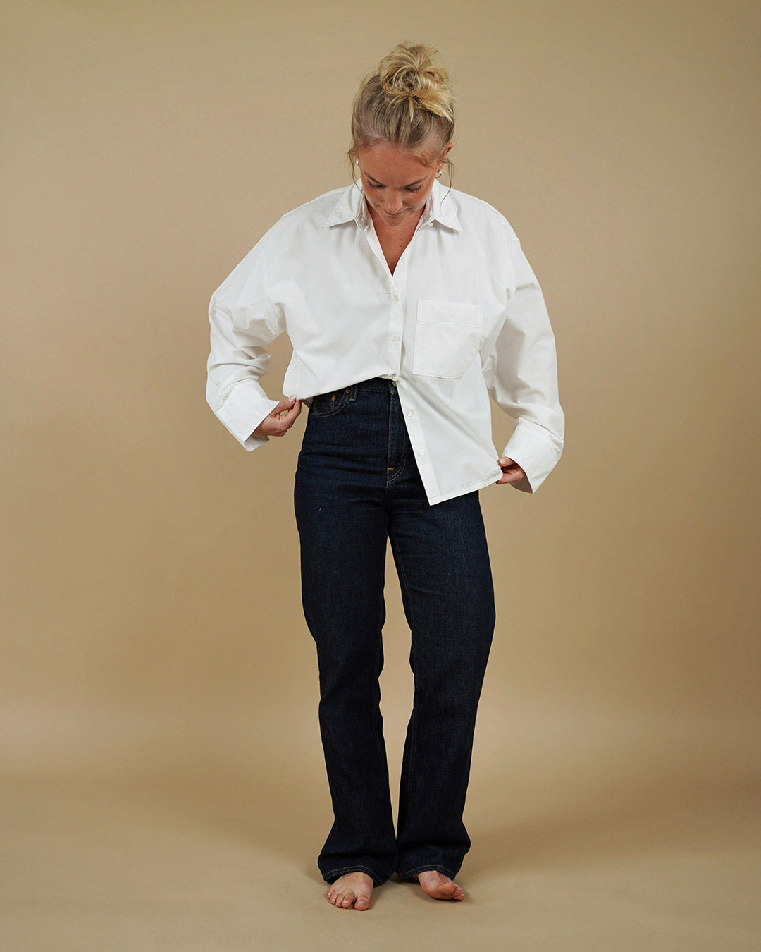 Woman wearing a white shirt and black pants on a beige background