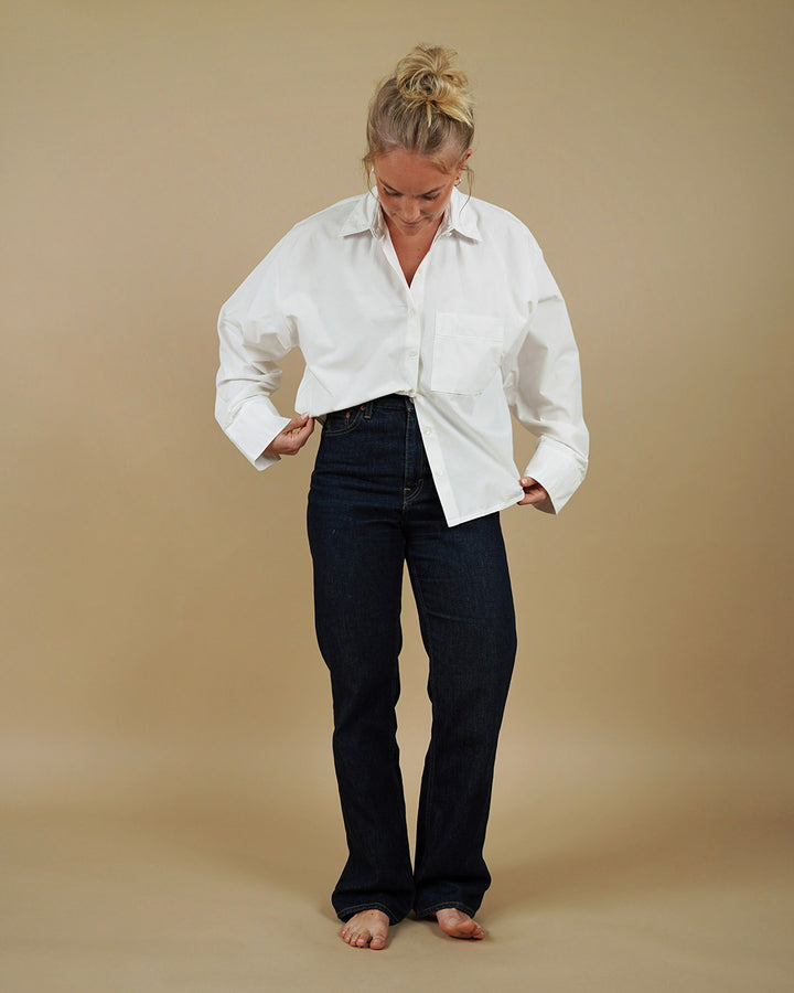 Woman wearing a white shirt and black pants on a beige background