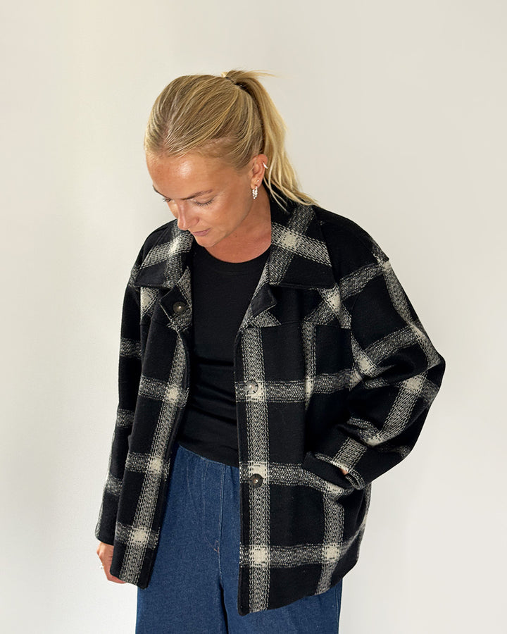 Person wearing a black and white checkered coat on a plain background