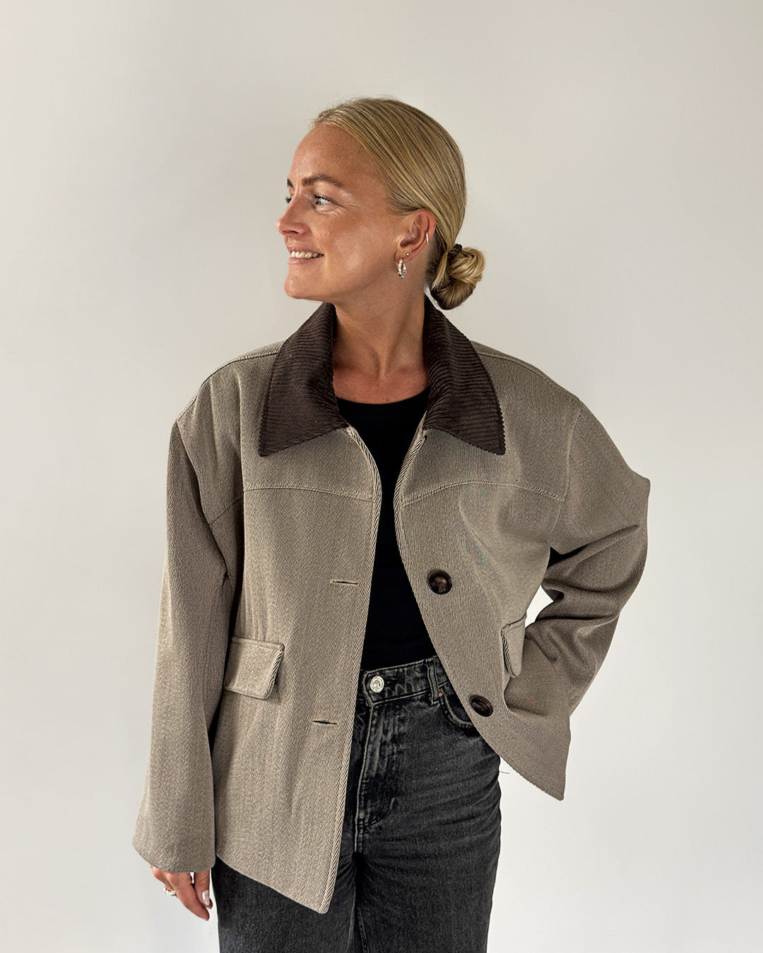 Woman wearing a beige jacket with a dark collar against a white background