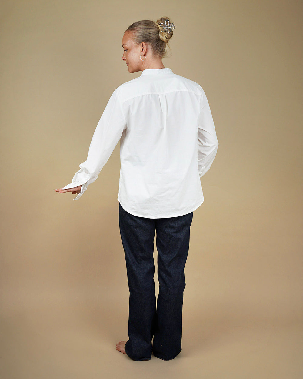 Person wearing a white Tunic and dark pants on a beige background