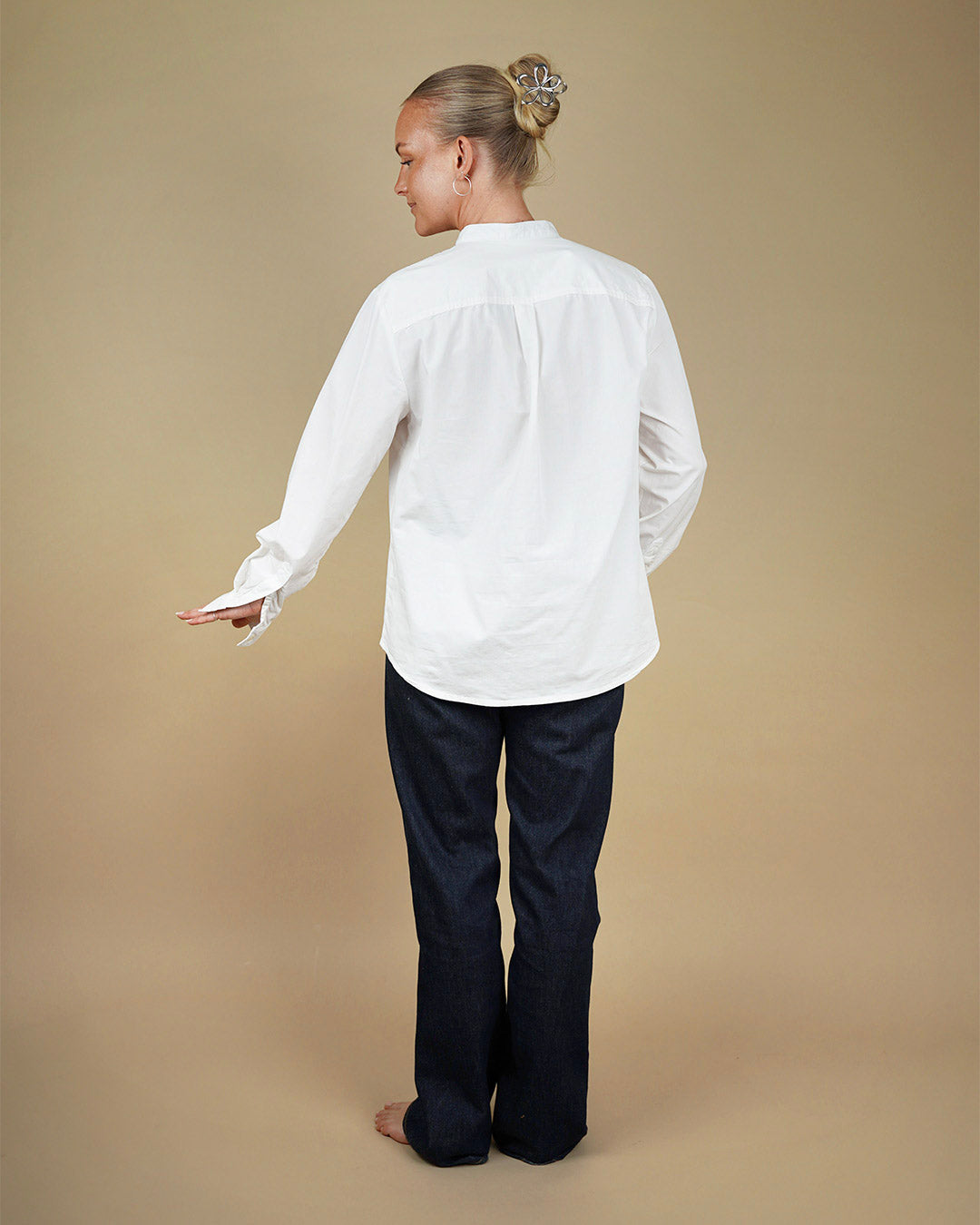 Person wearing a white Tunic and dark pants on a beige background