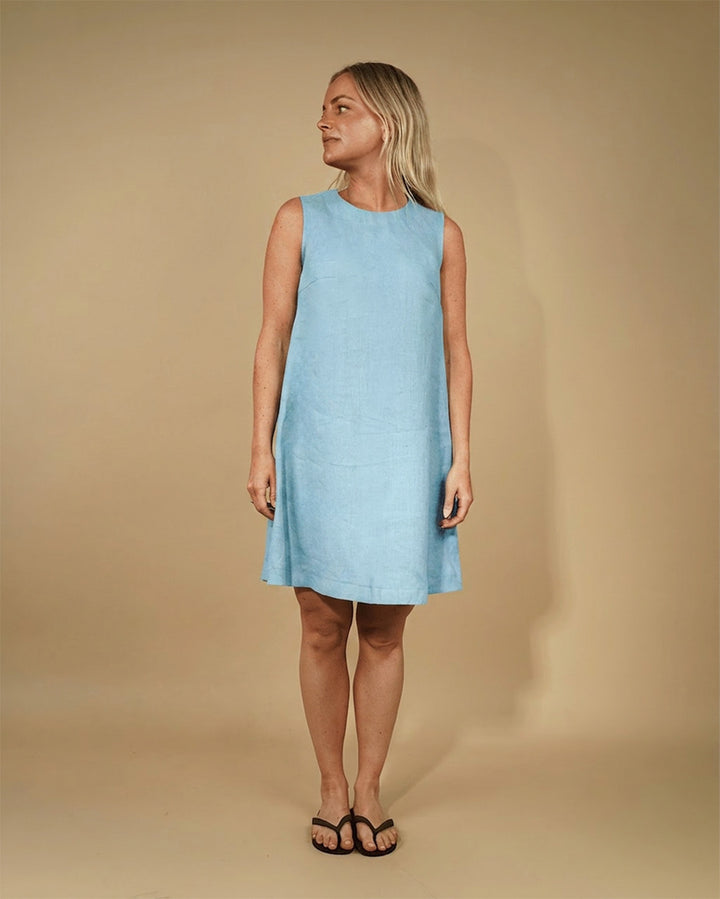 Woman wearing a light blue sleeveless dress against a beige background